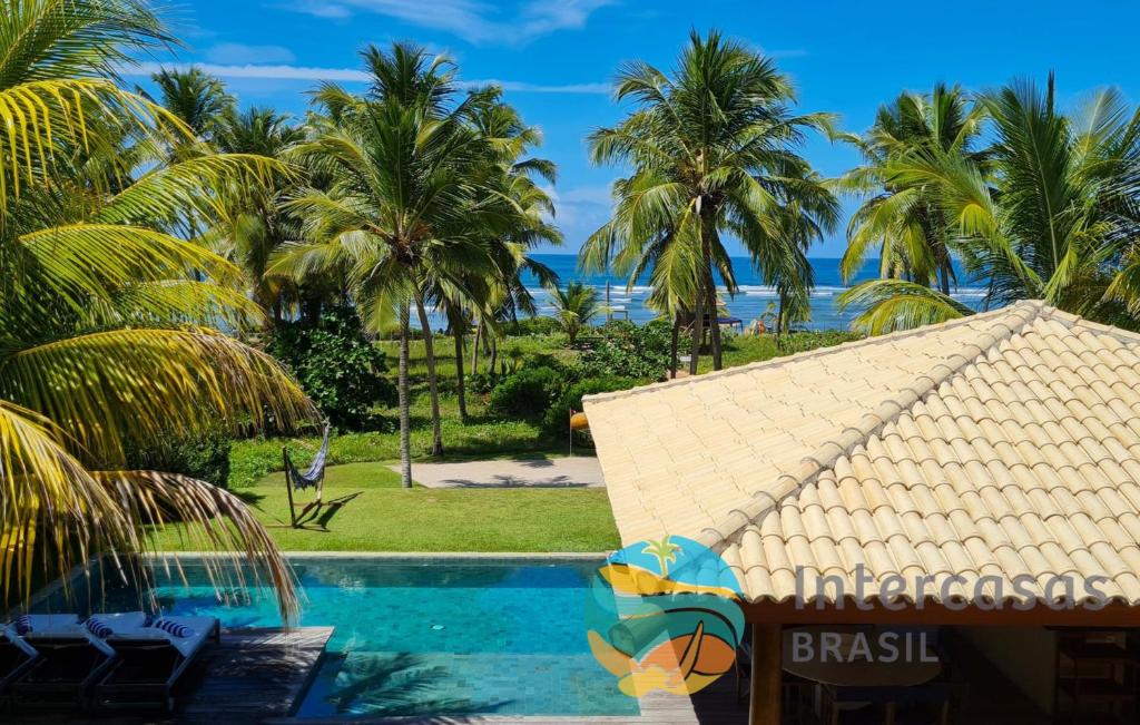 a resort with a swimming pool and palm trees at Villa Biarritz, Praia do Forte in Praia do Forte