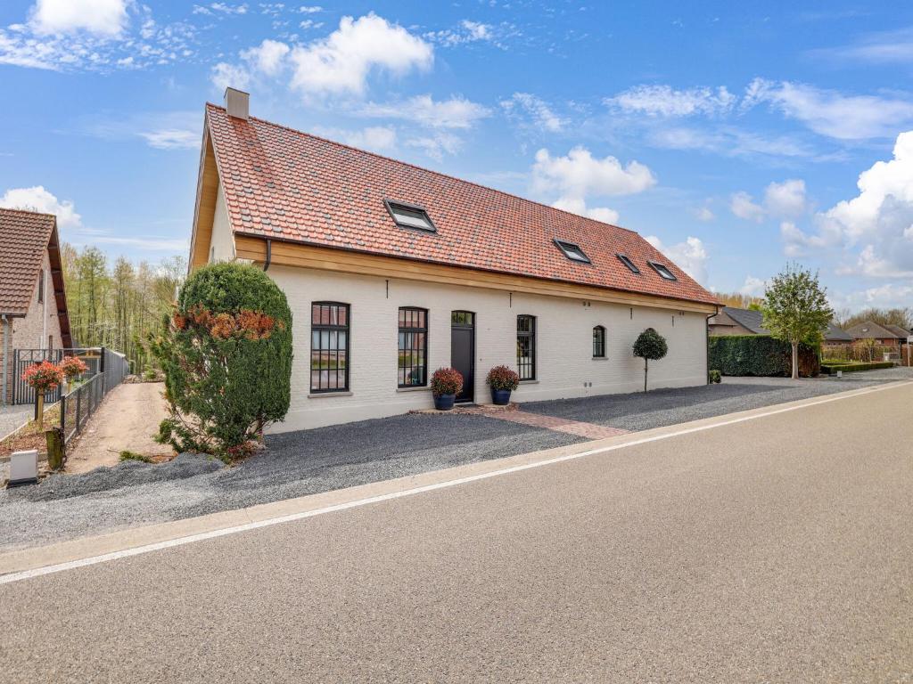 um edifício branco com um telhado vermelho numa rua em Luxurious 5-star house in Limburg with jacuzzi, a paradise for families em Bree