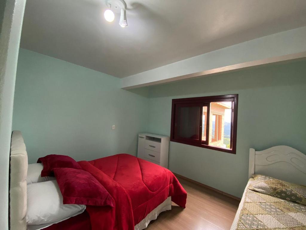 a bedroom with a red bed and a window at Casa Temporada Monte Belo do Sul in Monte Belo