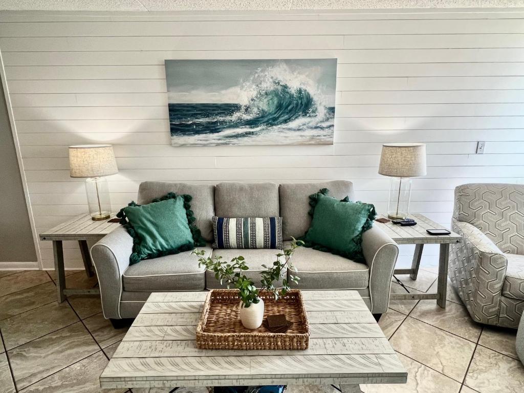 uma sala de estar com um sofá e uma onda na parede em Condo on the Beach- walk to restaurants, shops and activities. em Gulf Shores