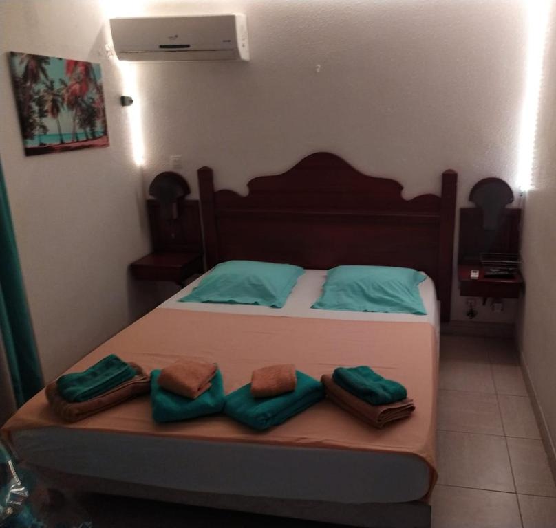 Un dormitorio con una cama con almohadas verdes. en La Martiniquaise, en Sainte-Anne