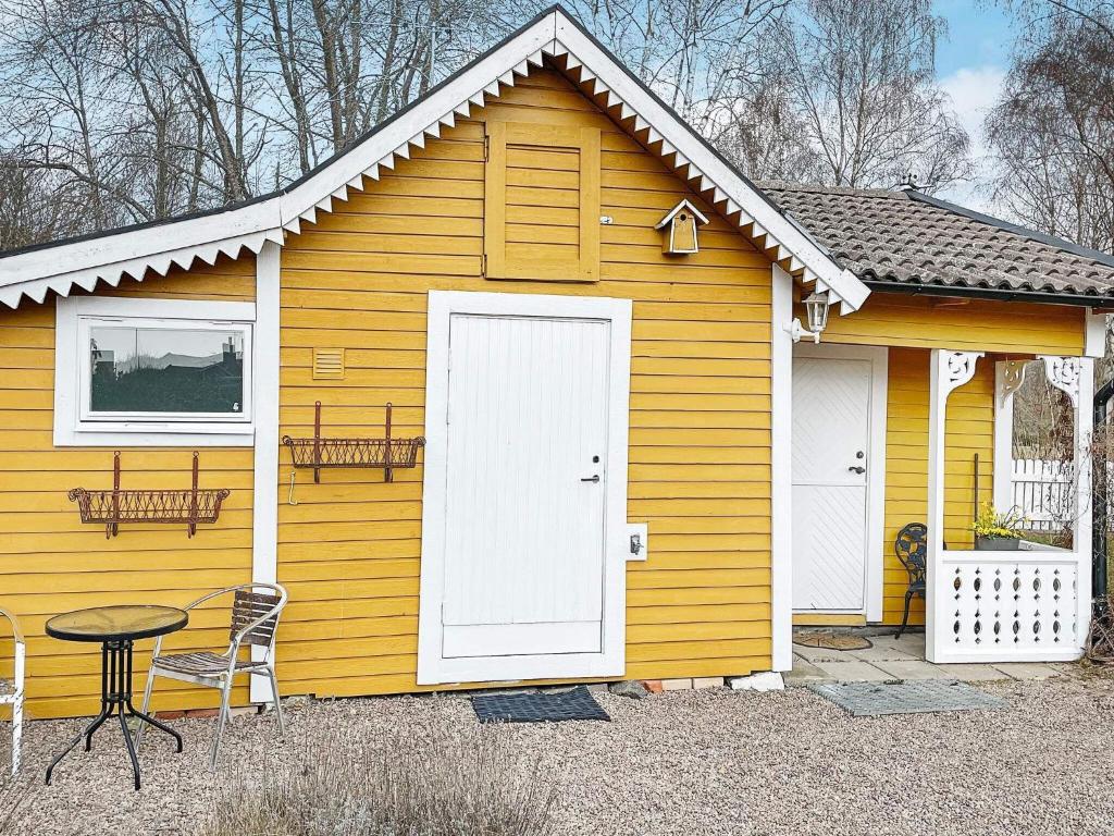 ein kleines gelbes Haus mit einer weißen Tür und einem Tisch in der Unterkunft Holiday home Ronneby VI in Ronneby