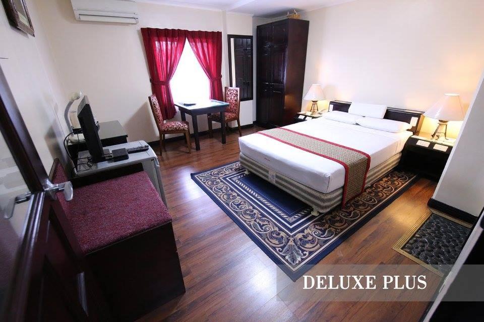 Una habitación de hotel con una cama y un escritorio y una habitación. en Hotel Asia Cebu, en Cebú
