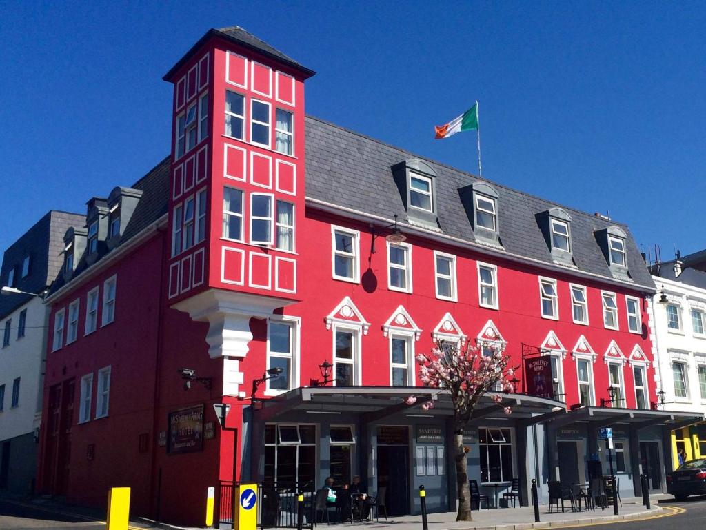 um edifício vermelho com uma bandeira em cima em McSweeney Arms Hotel em Killarney