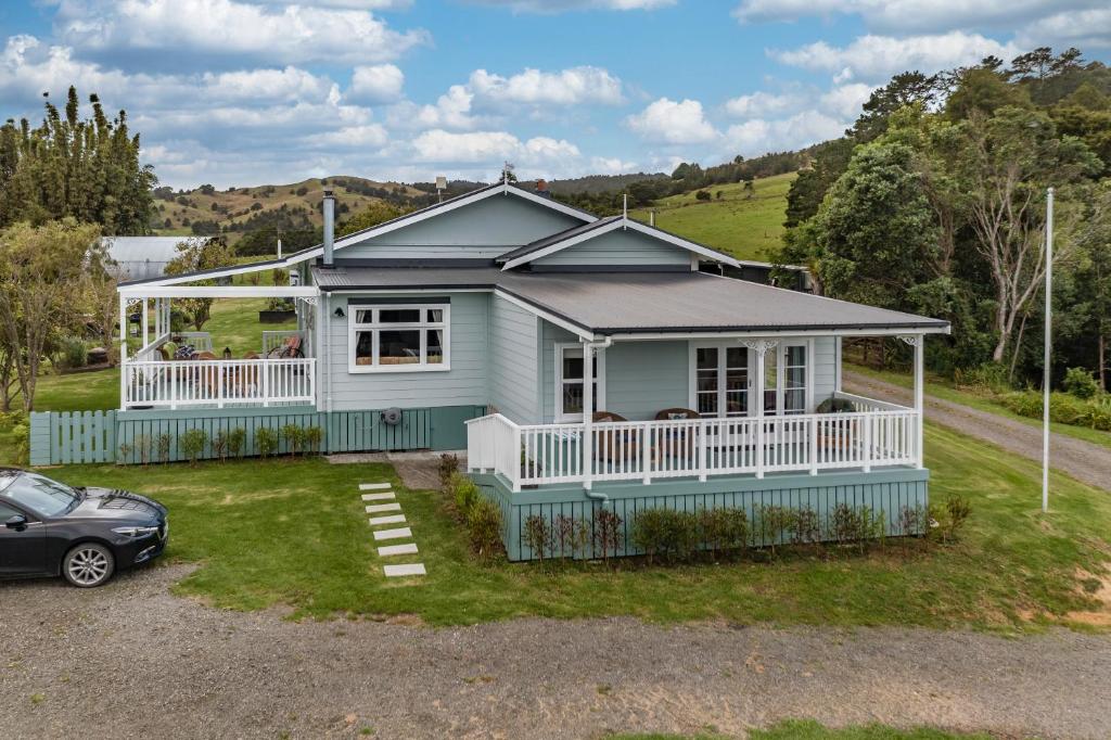 a blue house with a car parked in front of it at Harbour View in Kohukohu Town District