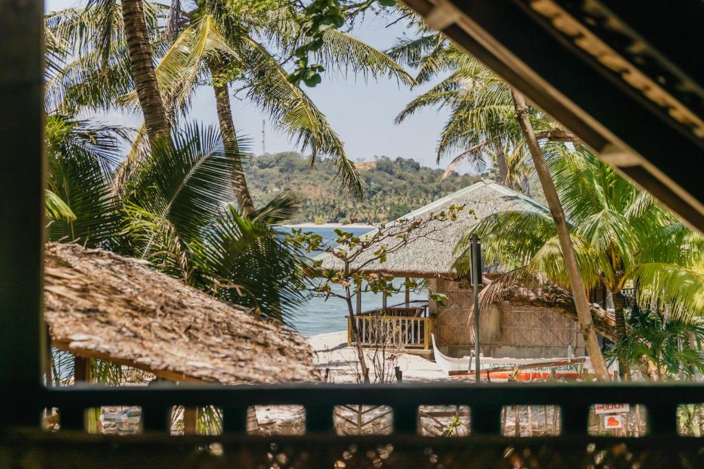 una ventana con vistas a una playa con palmeras en Amami Beach Resort en Puerto Galera