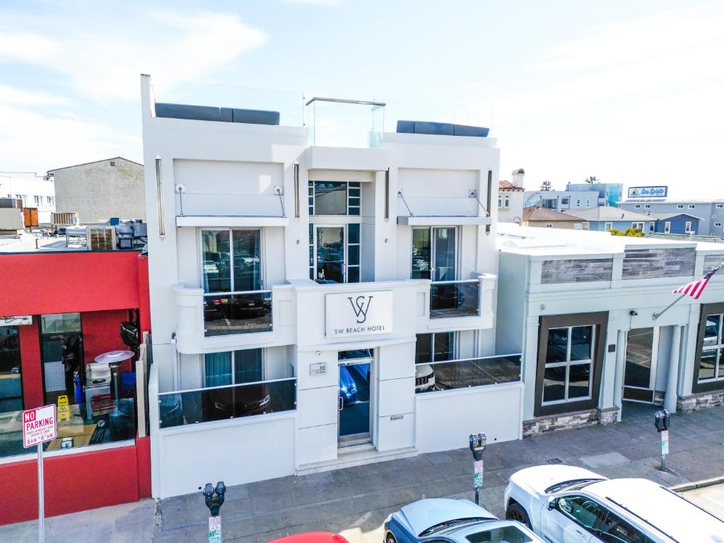 un edificio blanco con coches estacionados frente a él en SW Beach Hotel en Hermosa Beach