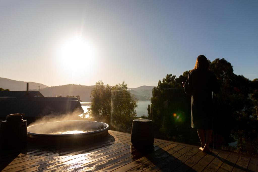 una mujer de pie junto a una bañera de hidromasaje en una terraza en Woodland Bay Retreat-Luxury Hamptons Retreat en Lymington