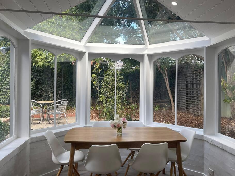 a conservatory with a wooden table and white chairs at Heritage cottage in South Hobart in Hobart