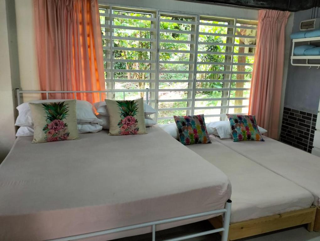 two beds in a room with a large window at CHALET MORIS D' RUMAH BONDA RIVER VIEW in Kampong Senawar