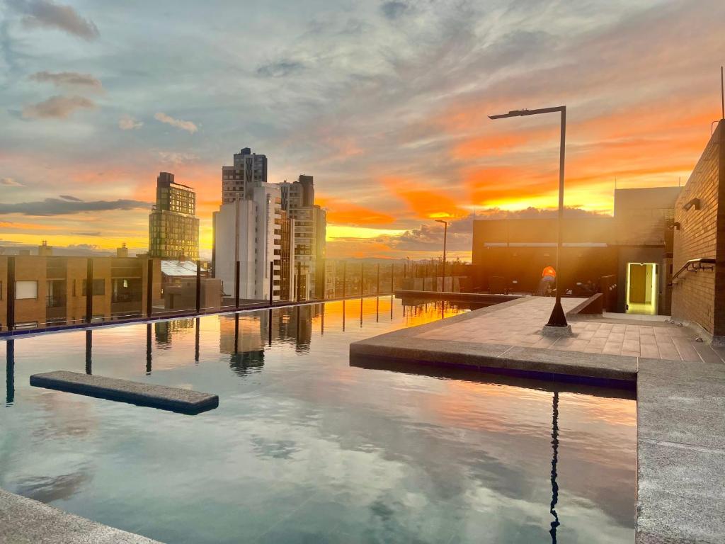 a pool on top of a building with a sunset at Loft/Apartaestudio Chapinero con piscina gym in Bogotá