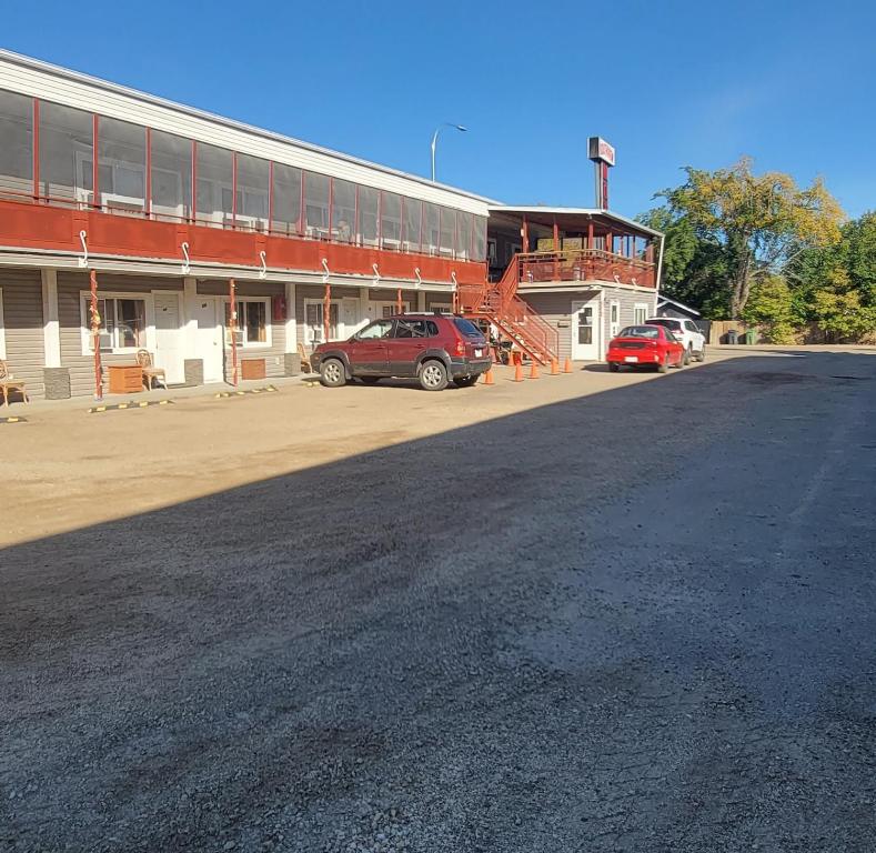 ein rotes Auto, das vor einem Gebäude parkt in der Unterkunft Southview Motel in Westlock