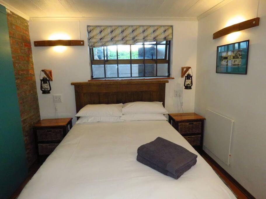 a bedroom with a large white bed with a window at De Kelder in Cape Town