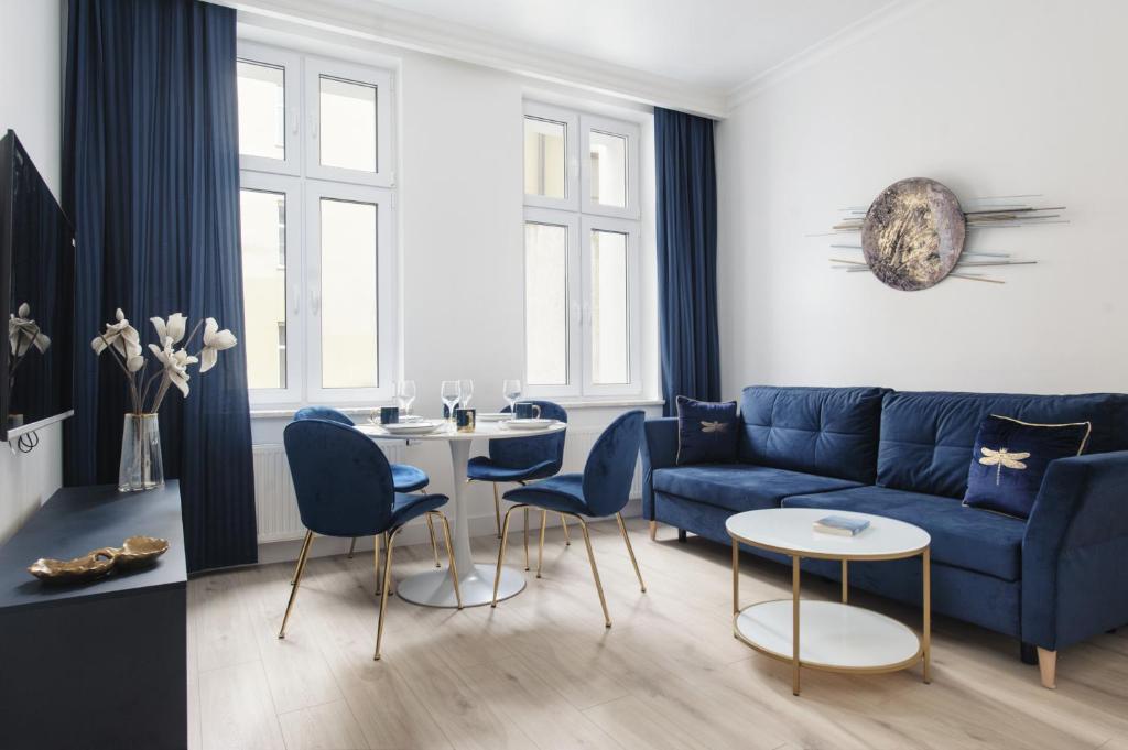 sala de estar con sofá azul y sillas en Manpro Apartments Toruń, en Toruń