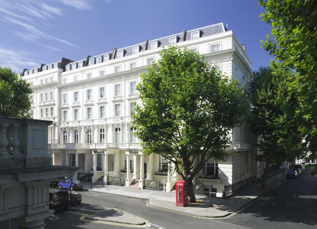 un edificio bianco con una cabina telefonica rossa davanti di Berjaya Eden Park London Hotel a Londra