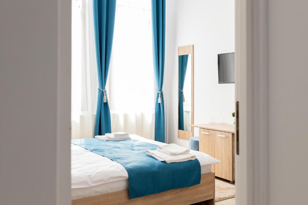 Schlafzimmer mit einem Bett mit blauen Vorhängen und einem Waschbecken in der Unterkunft MARCONI GUESTHOUSE in Hunedoara