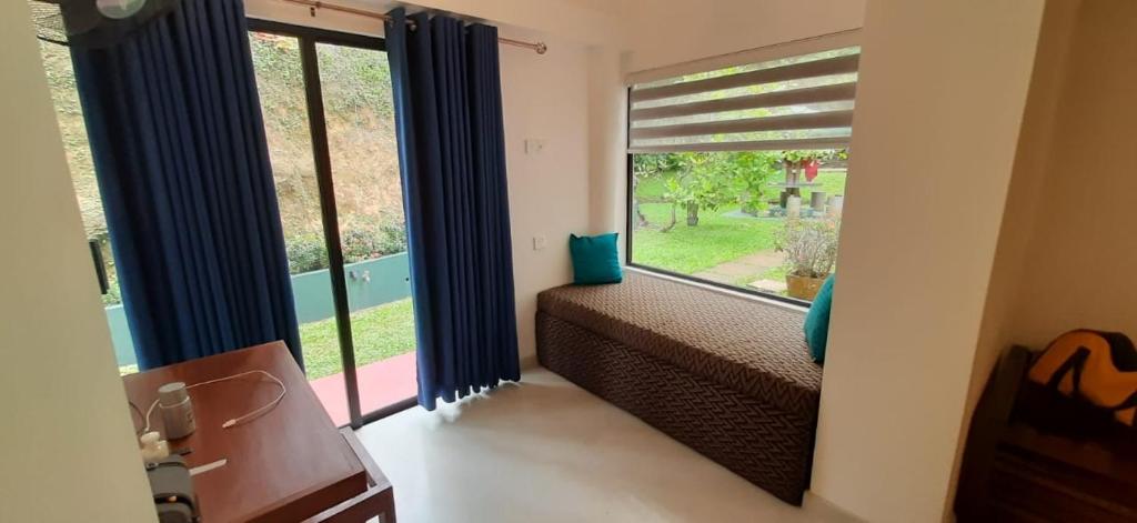 a room with a large window with blue curtains at HangarankandaBungalow Deniyaya in Deniyaya