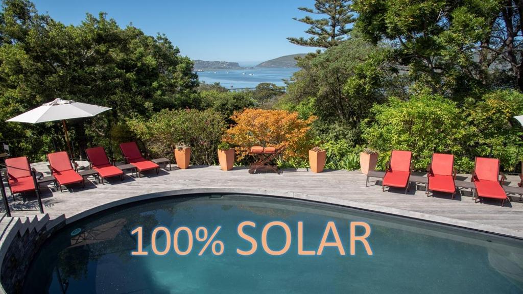 a swimming pool with chairs and a sign with the words solar at Double Dutch B & B in Knysna