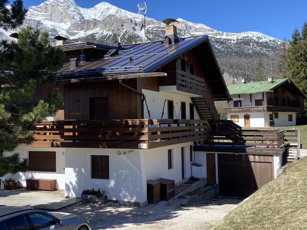 a house with a roof with mountains in the background at Casa Ca dei Pini in Cortina dʼAmpezzo