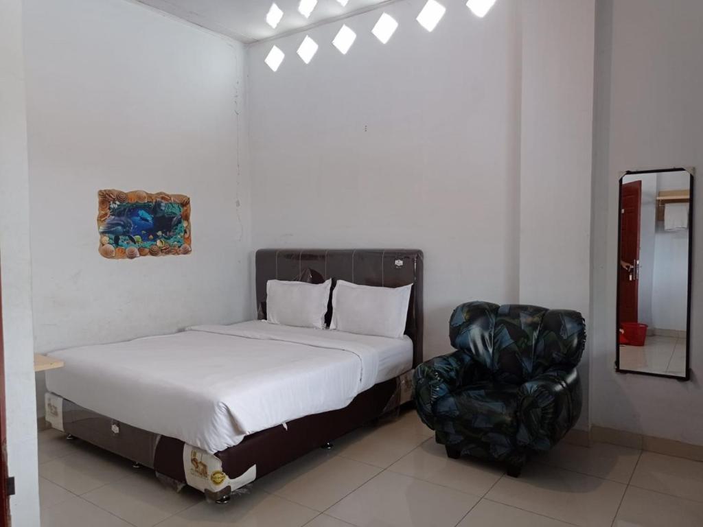 um quarto com uma cama e uma cadeira preta em DAMAI GUEST HOUSE LAUCIMBA KABANJAHE em Kabanjahe