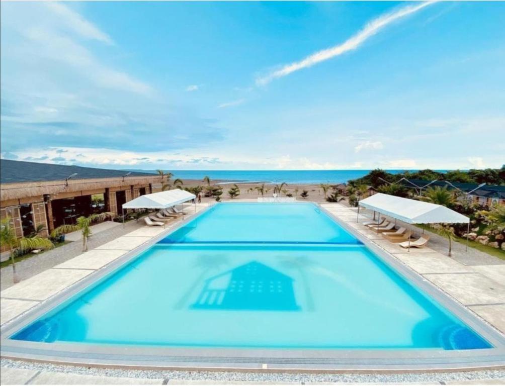 a large swimming pool with a view of the ocean at LaSersita Casitas and Water Spa Beach Resort by Cocotel 