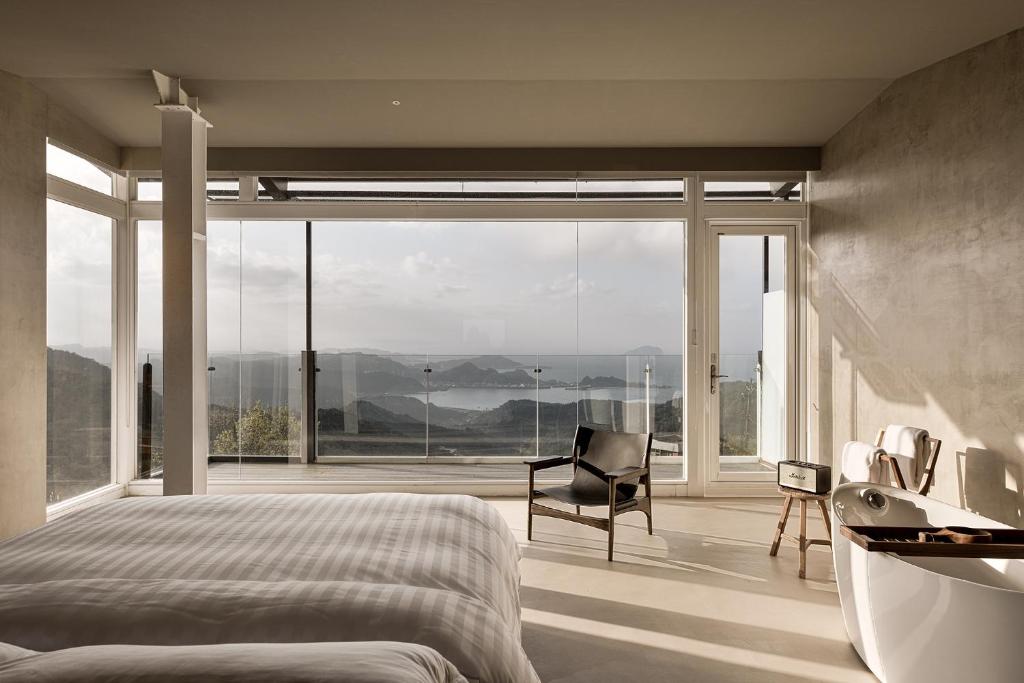 een slaapkamer met een bed, een bad en een stoel bij Daybreak in Jiufen