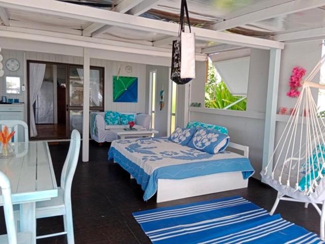 a bedroom with a bed and a table and a swing at Poppies Beach Bach in Matavera
