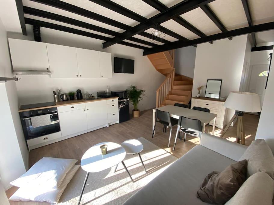 een keuken en een woonkamer met een bank en een tafel bij Appart rénové en duplex avec terrasse et garage in Bouleurs