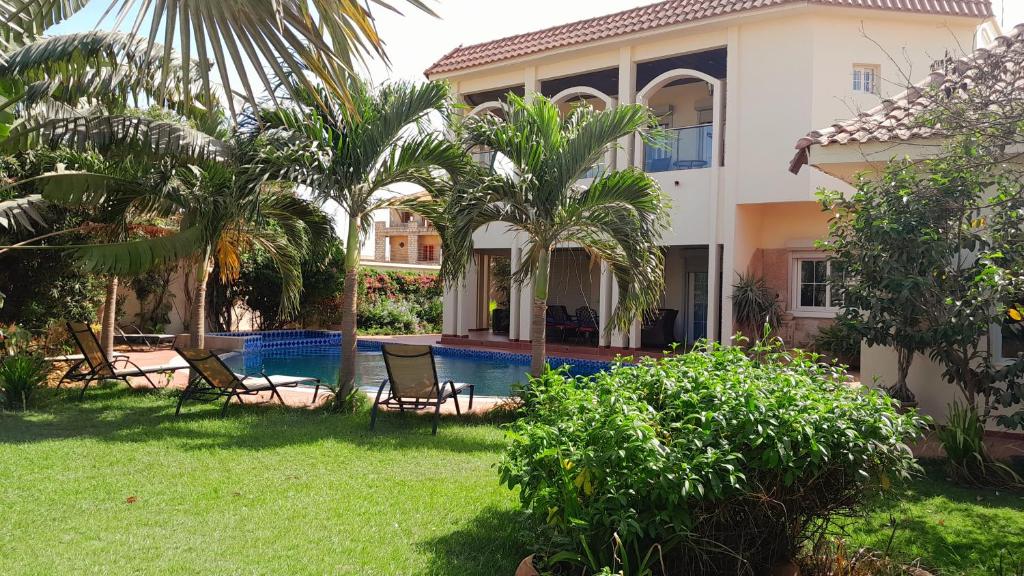 a villa with a swimming pool and palm trees at villa térangart saly in Saly Portudal