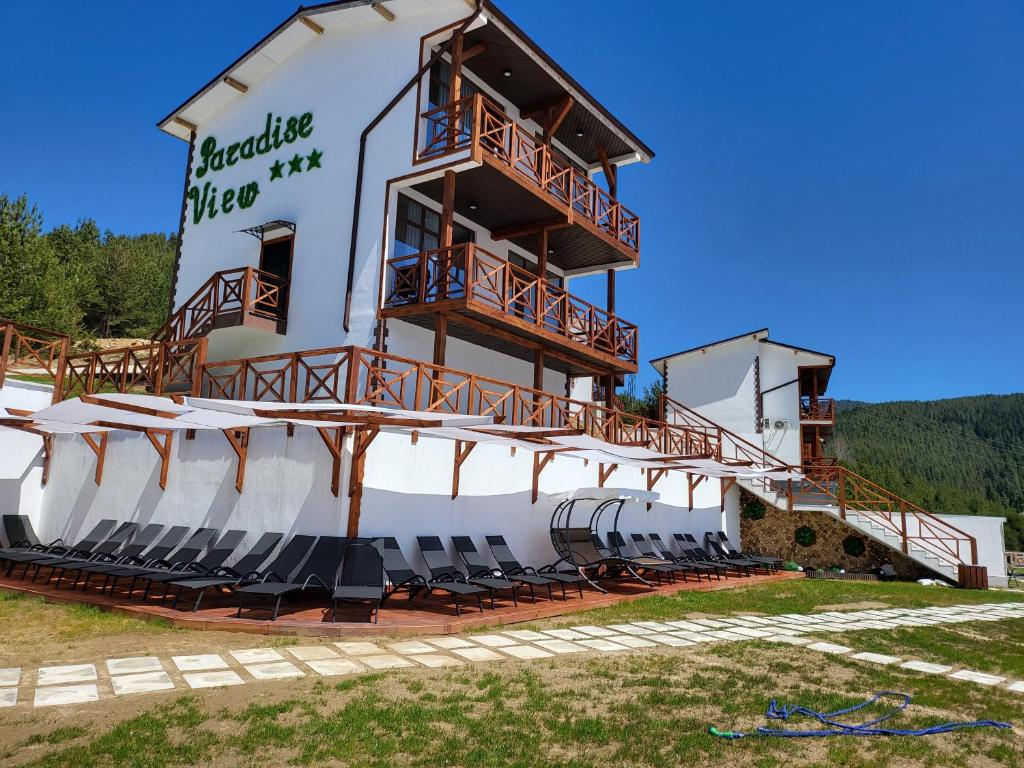 a building with chairs and a balcony on it at Вилно селище PARADISE VIEW in Sarnitsa