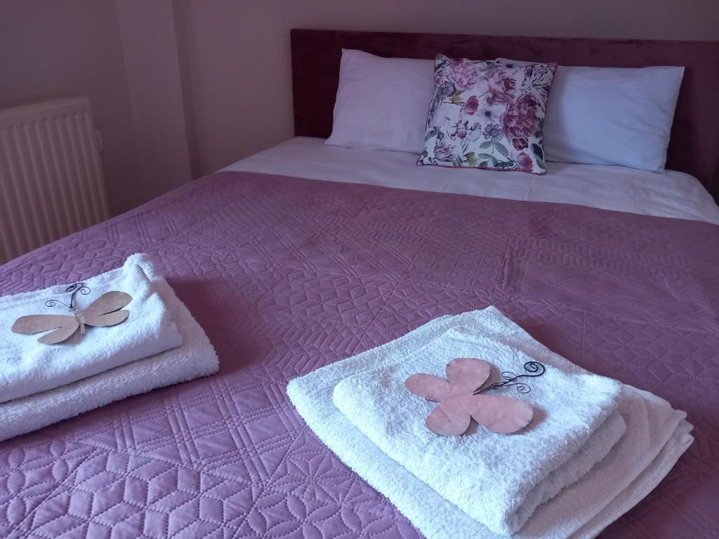 two towels on a bed with pink sheets and butterflies at Selene's House in Skala Kallirachis