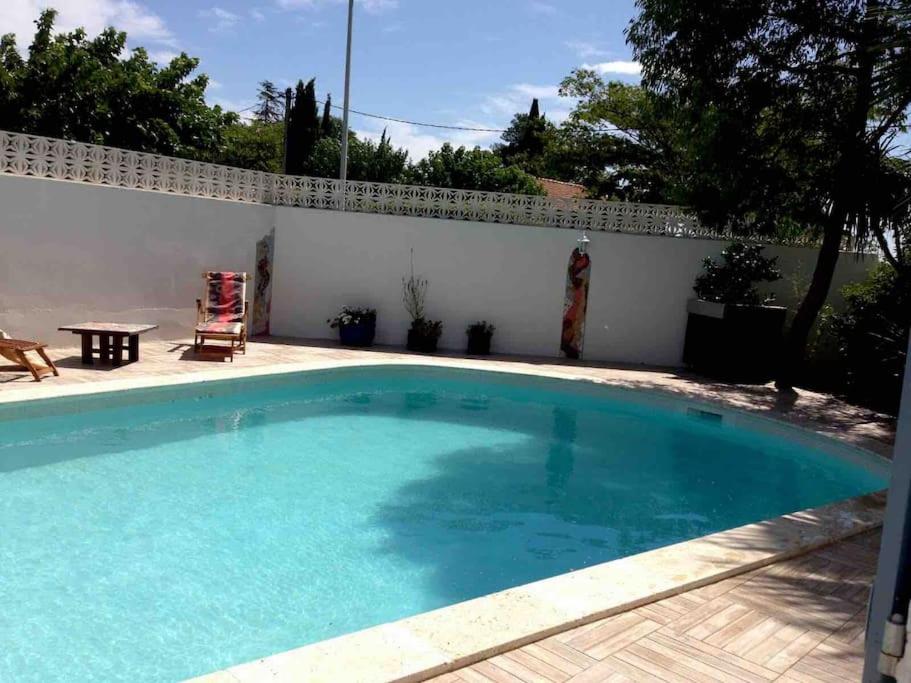 una piscina in un cortile con una parete bianca di Appartement 2 pièces avec piscine et jardin privés a Pailhès