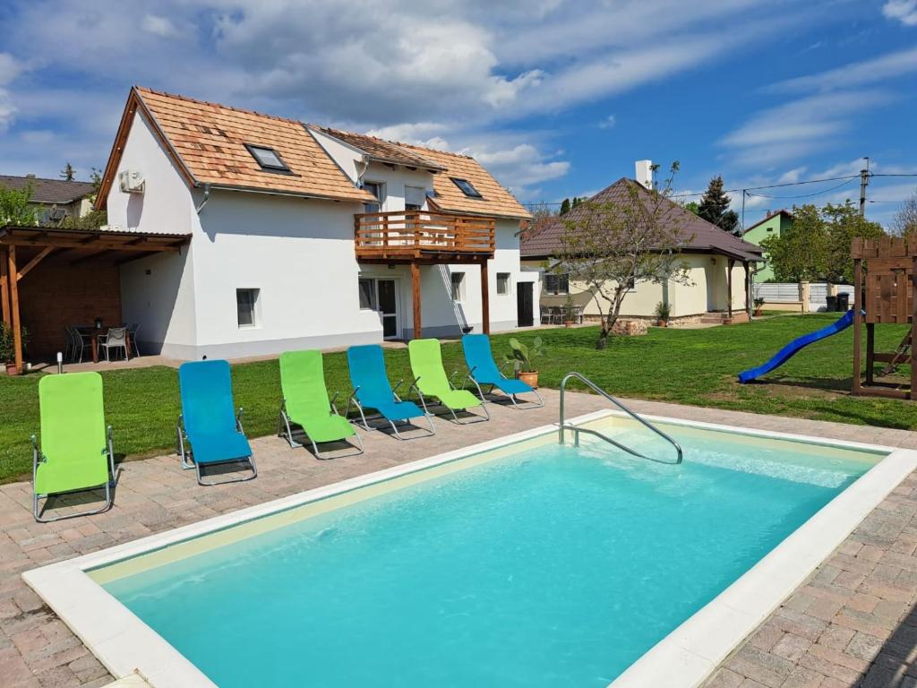 a swimming pool with chairs and a house at Amande House & Cottage in Vonyarcvashegy
