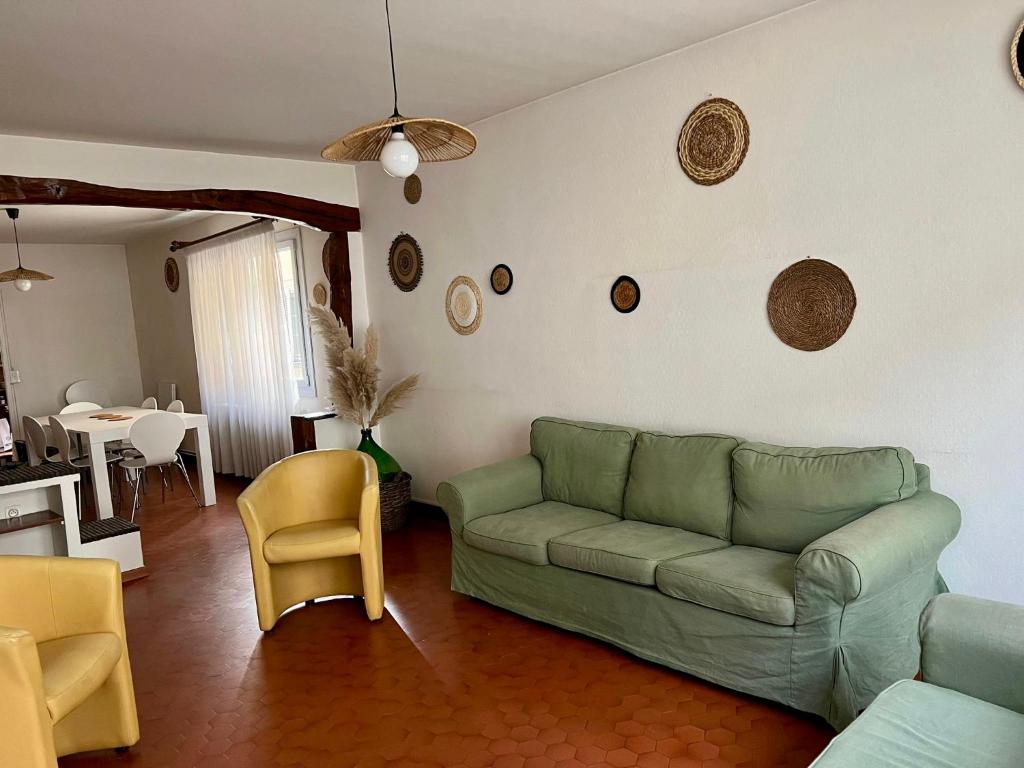 - un salon avec un canapé vert et des chaises dans l'établissement Appart patio véranda terrasse , à Arbois