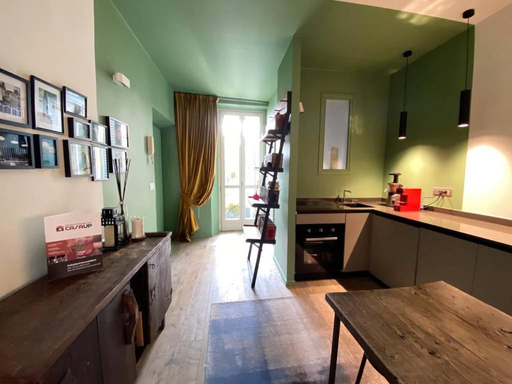 a kitchen with green walls and a wooden table at Da Amélie - Casa Ludovica nel cuore della Gran Madre a Torino in Turin