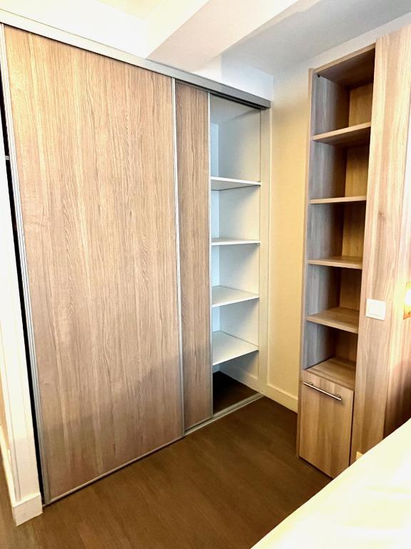 a closet in a bedroom with wooden cabinets at Maïa YourHostHelper in Caen