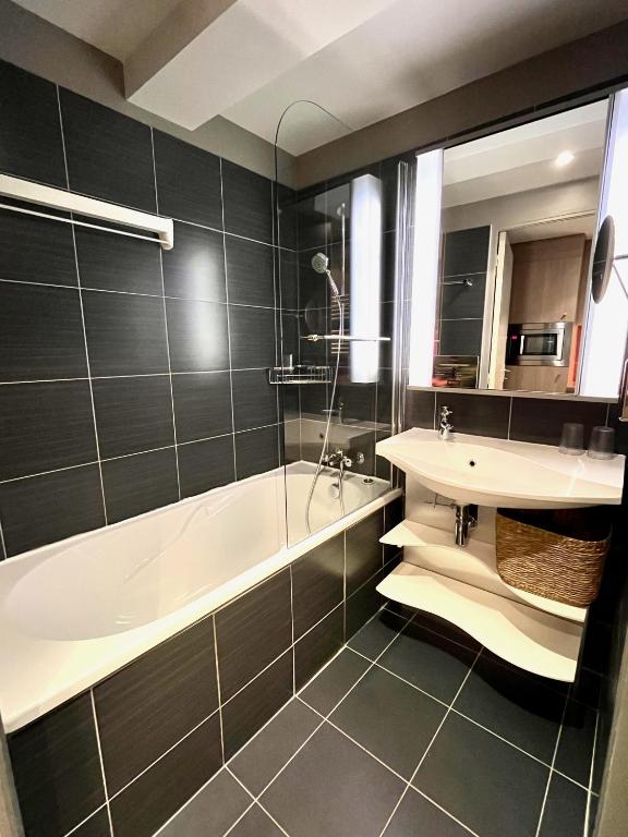a bathroom with a bath tub and a sink at Maïa YourHostHelper in Caen