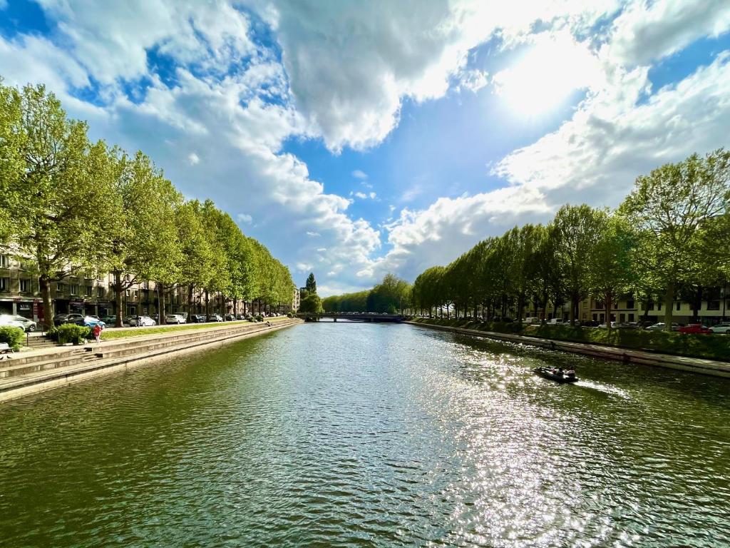 a river in a city under a cloudy sky at Maïa YourHostHelper in Caen