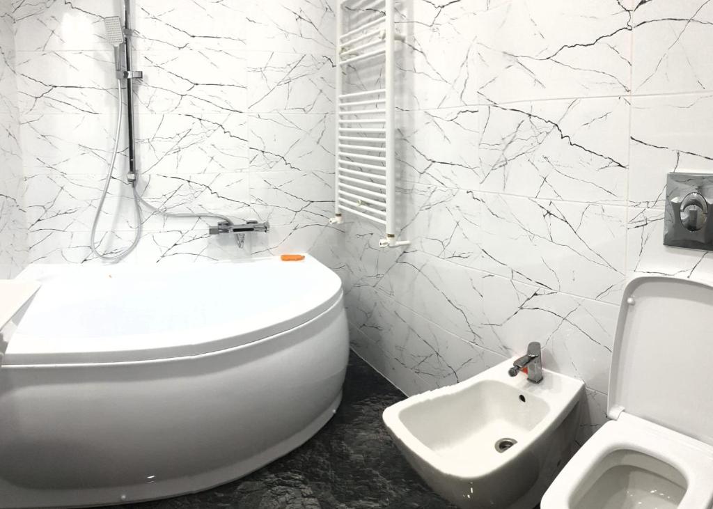 a white bathroom with a toilet and a sink at Garsoniera in Dorohoi