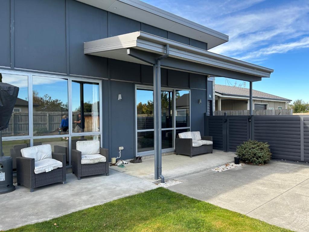 a patio with two chairs and awning on a house at Modern on McMillan in Methven