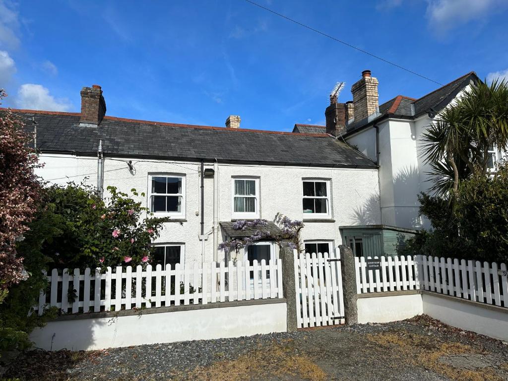 a white house with a white picket fence at Feock beautiful sunny cottage in Truro