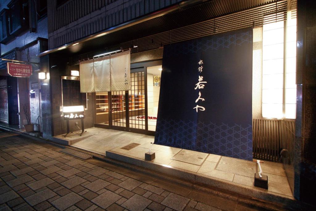 un frente de tienda con un cartel en el lateral de un edificio en Ryokan Wakamiya, en Kioto