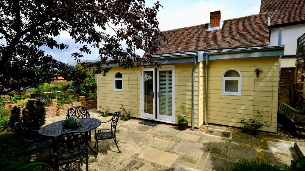 una piccola casa gialla con tavolo e sedie di The Garden Room a Woodbridge
