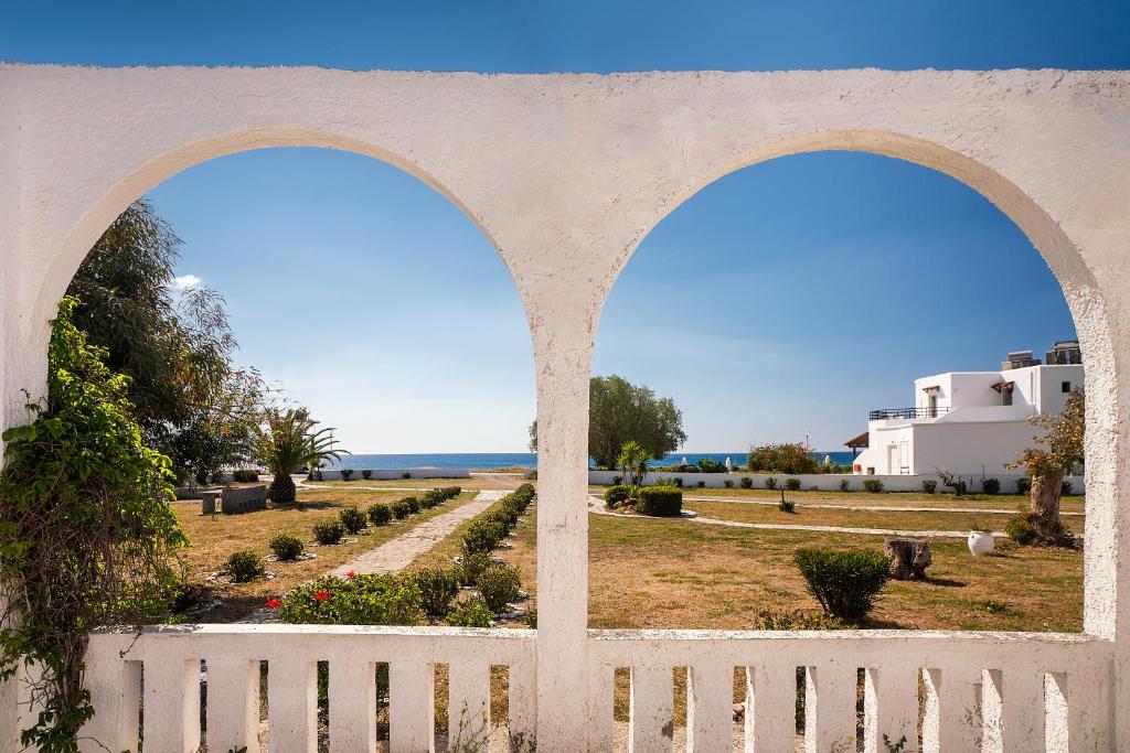 due archi sopra una recinzione bianca e un giardino di Kiotari beach garden view-sea view a Kiotari