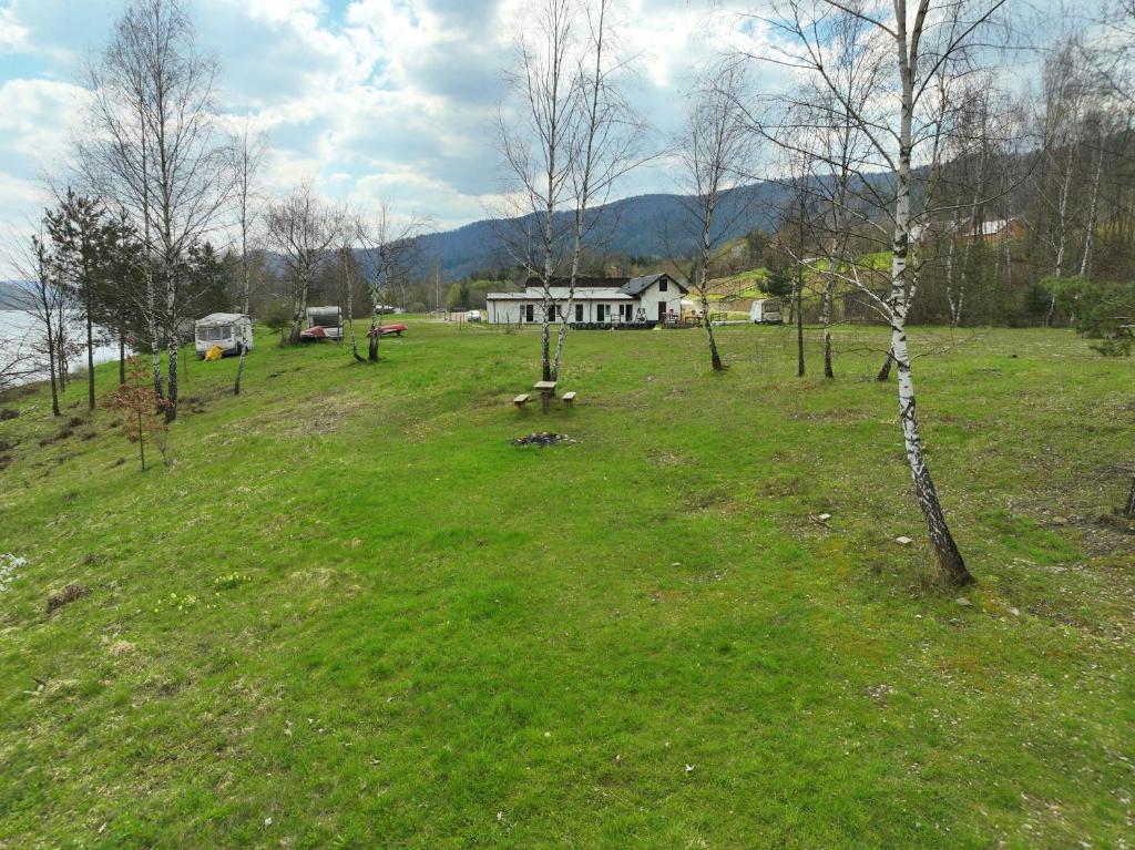 um campo relvado com uma casa ao fundo em Słoneczna Przystań Klimkówka pokoje camp pole namiotowe em Klimkówka