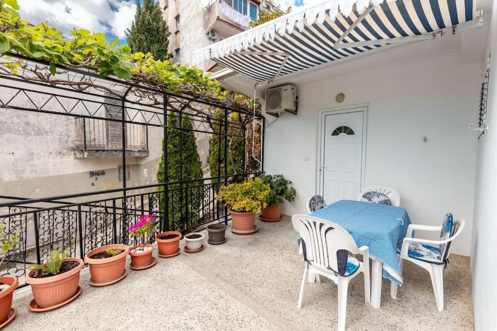 um pátio com uma mesa, cadeiras e vasos de plantas em Solo Sole apartman 1- Meljine em Meljine