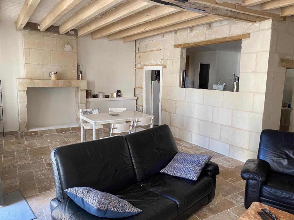 uma sala de estar com um sofá de couro preto e uma mesa em maison cœur de village em Sainte-Catherine-de-Fierbois