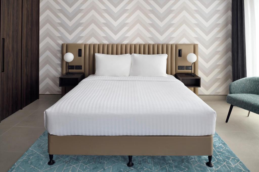 a bedroom with a large bed and a chair at Courtyard by Marriott World Trade Centre, Dubai in Dubai
