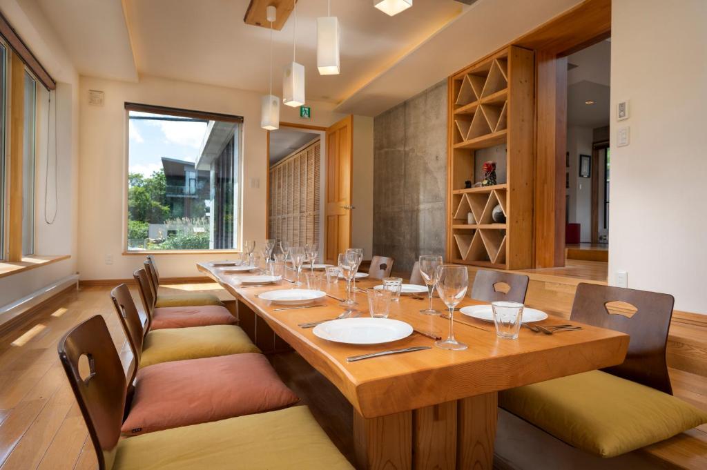 a dining room with a long wooden table and chairs at Asobidokoro in Kutchan