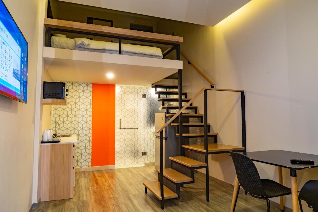A loft-style room combining a raised bed, dining table and compact kitchenette.